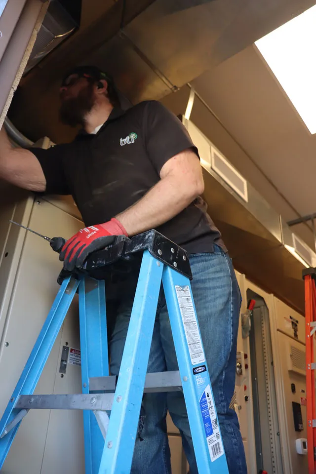 BTI technician on a ladder installing a security camera