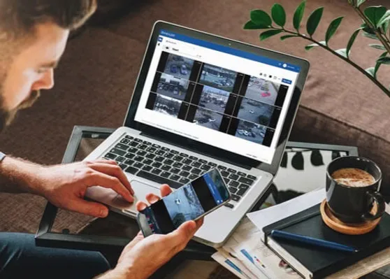 Person monitoring Avigilon ACC app though a laptop and his phone