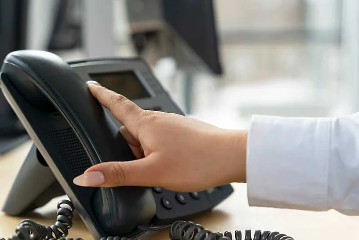 Close-up person hanging up a phone in a call center.