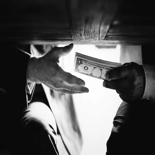 Man passing money under the table representing hidden crime tax