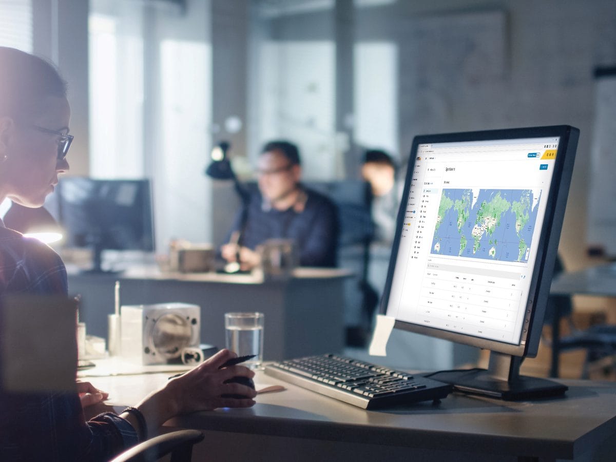 Operator viewing Axis multisite audio management software with floor plans on a monitor