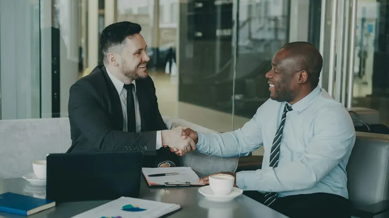 BTI advisor shaking hands with a business client across a meeting table after reviewing their communications contracts
