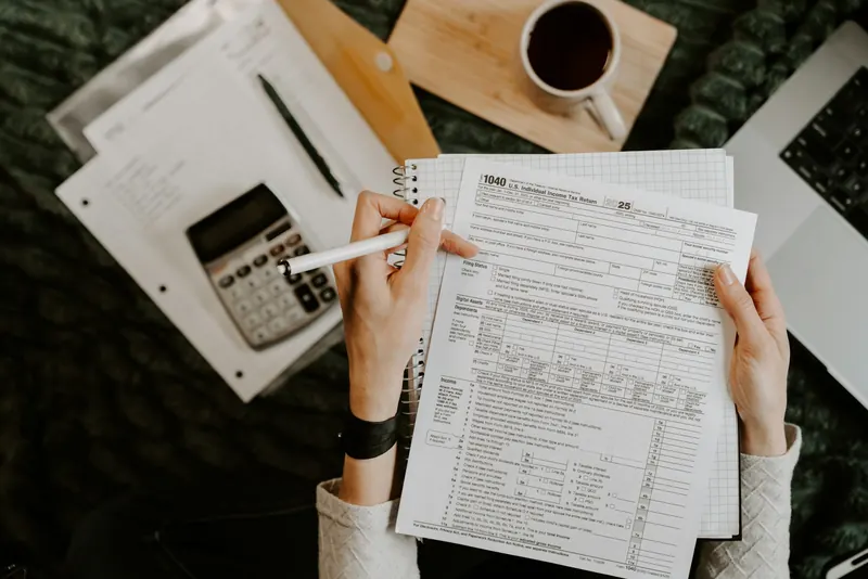 Hands reviewing itemized telecom invoices and contract terms with a calculator