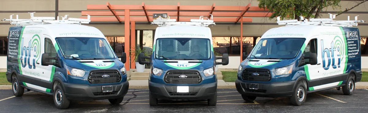 Three BTI Communications Group service vans parked side by side, ready for on-site IT support calls across Chicagoland